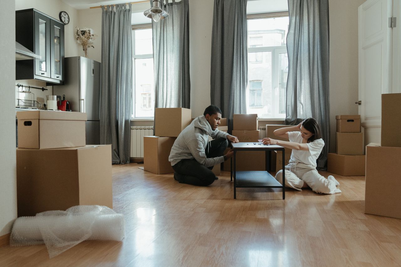 gallery-2 Young couple putting together furniture in their new apartment, with cardboard boxes all around them.